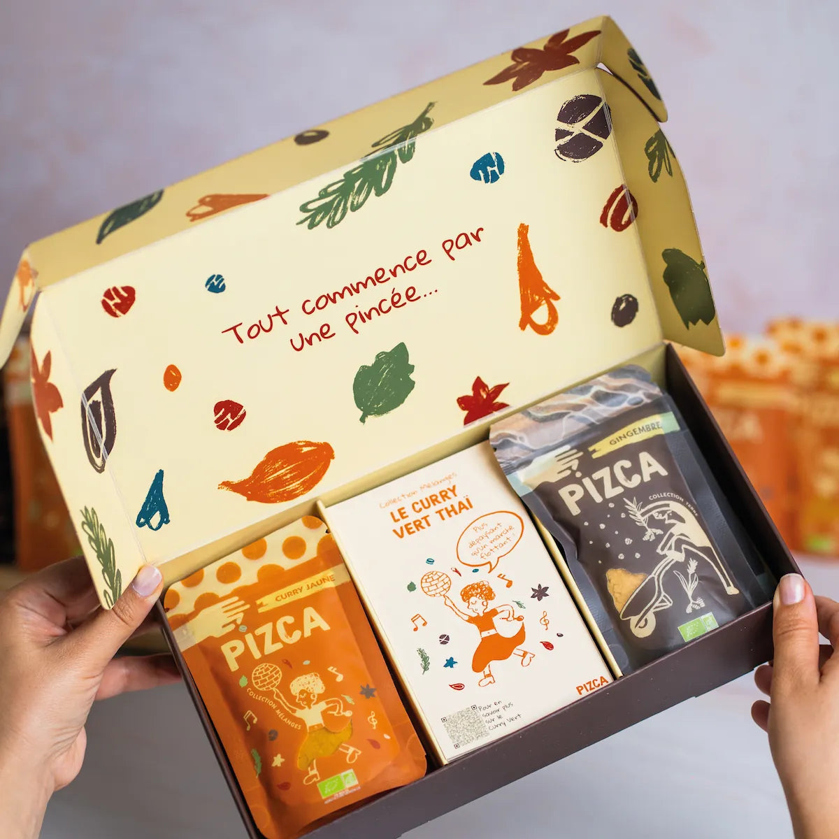 Coffret cadeau d'épices bio Pizca ouvert contenant un sachet de gingembre et un sachet de curry jaune et une fiche recette de curry vert avec un design illustré moderne